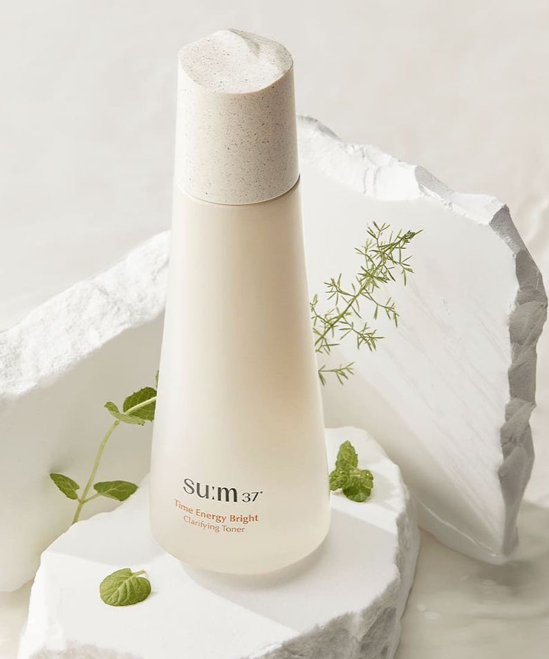 SU:M37 Time Energy Bright Clarifying Toner 170ml, élégant et rafraîchissant, au milieu de textures naturelles blanches.