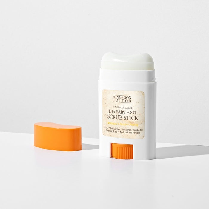 SUNGBOON EDITOR Laha Baby Foot Scrub Stick en stick blanc et orange sur fond blanc, marque visible, produit beauté.