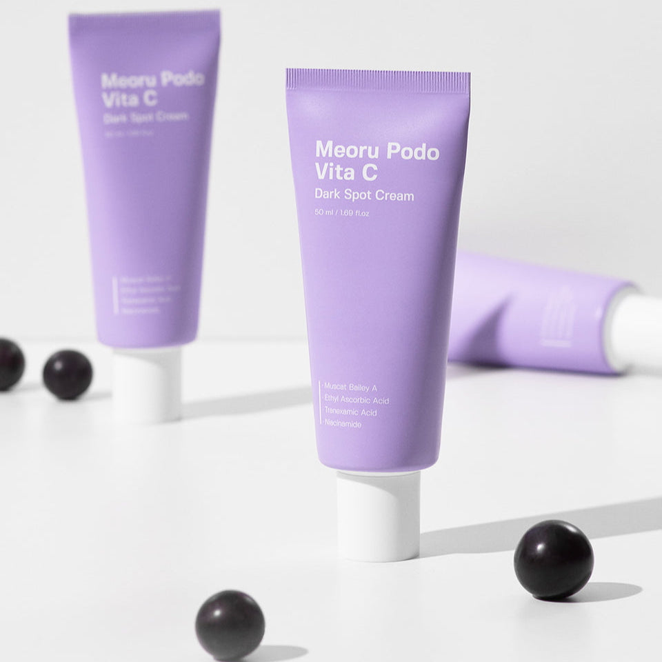 SUNGBOON EDITOR Meoru Podo Vita C Dark Spot Cream 50ml sur fond blanc, tubes violets et billes noires, contexte beauté.