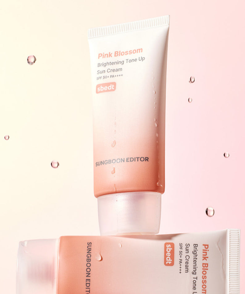 SUNGBOON EDITOR Pink Blossom Brightening Tone-Up Sunscream 50ml exposé avec éclaboussures d'eau, fond rose harmonieux.