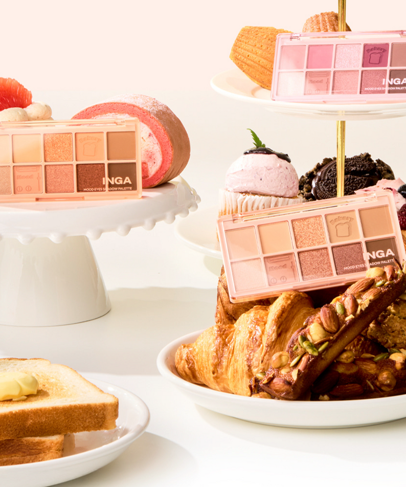 Palette INGA Mood Eyes Shadow entourée de pâtisseries variées, mettant en valeur les couleurs luxueuses et vibrantes du maquillage.