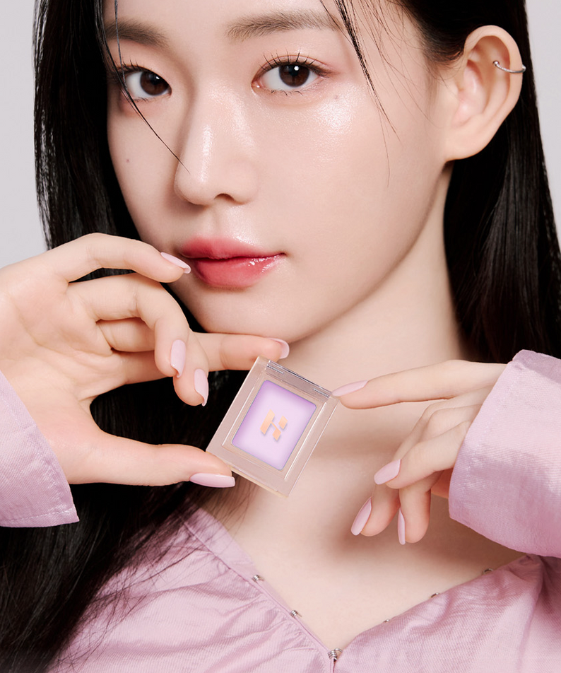 Femme tenant un HOLIKA HOLIKA My Favorite Peace Concealer avec un maquillage élégant, mettant en valeur la beauté naturelle du produit.