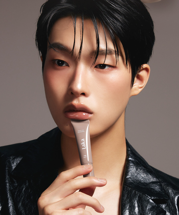 Homme tenant LAKA Fruity Lip Glossionner, maquillage audacieux et brillance, cosmétique tendance.