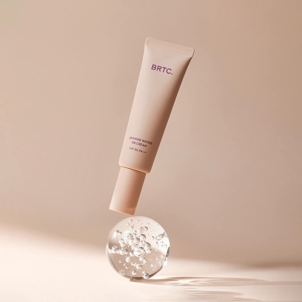 BRTC Jasmine Water BB Cream 60g de la marque BRTC, tube beige sur fond beige avec gouttes de texture, studio maquillage