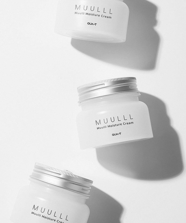 Bocaux de QUA-T Subuji Moisture Cream 100ml en plastique blanc avec couvercles argentés, disposés artistiquement sur fond blanc.