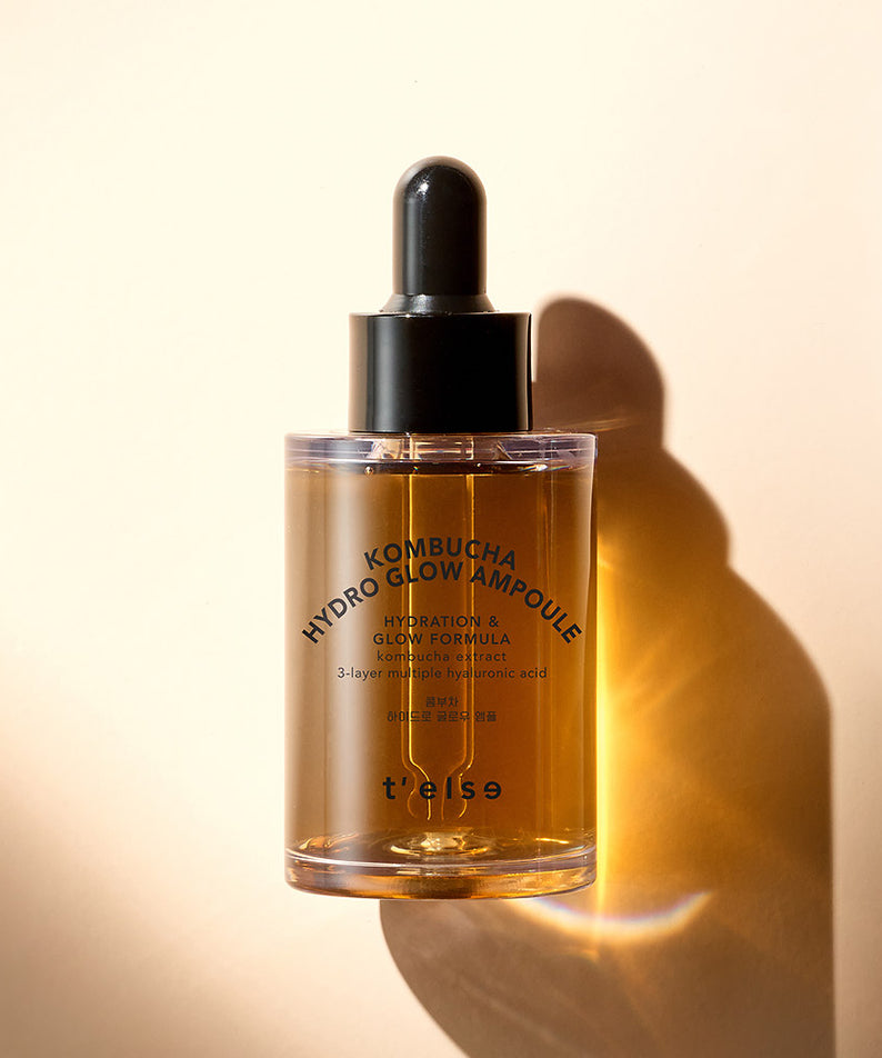 T'ELSE Kombucha Hydro Glow Ampoule 30ml, flacon d'élixir hydratant pour une peau éclatante sous la lumière dorée.