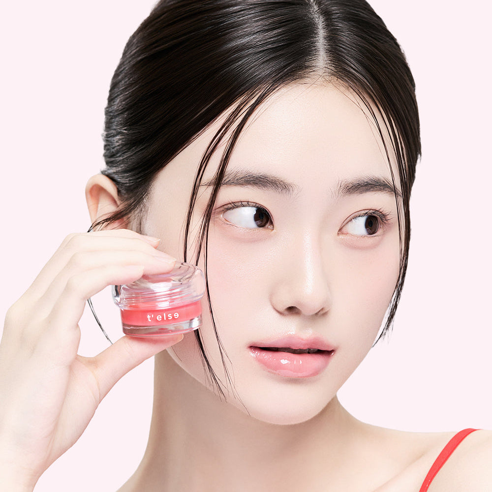 Décris l’image en français : T'ELSE Plumping Glow Jelly Pot 9g, marque T'ELSE, pot cosmétique tenu par une femme sur fond clair.
