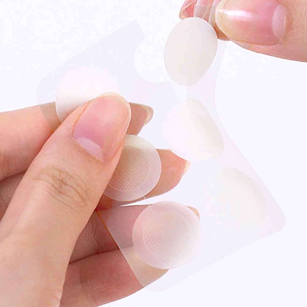 THE SAEM Golden Berry C Dark Spot Patch : mains appliquant des patchs sur la peau, photo produit marque THE SAEM.