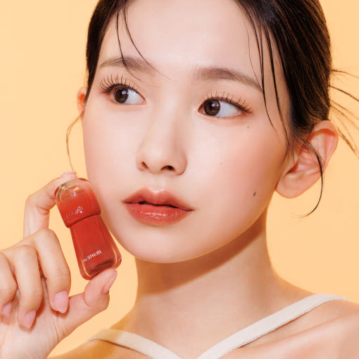 THE SAEM Saemmy's Aid Shot Tint, produit de la marque THE SAEM, sur une femme tenant le flacon rouge en studio.