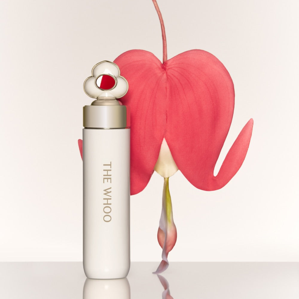 THE WHOO Essentail Lip Glow Balm de la marque THE WHOO, tube blanc sur fond clair, éclat et cœur rose rouge.