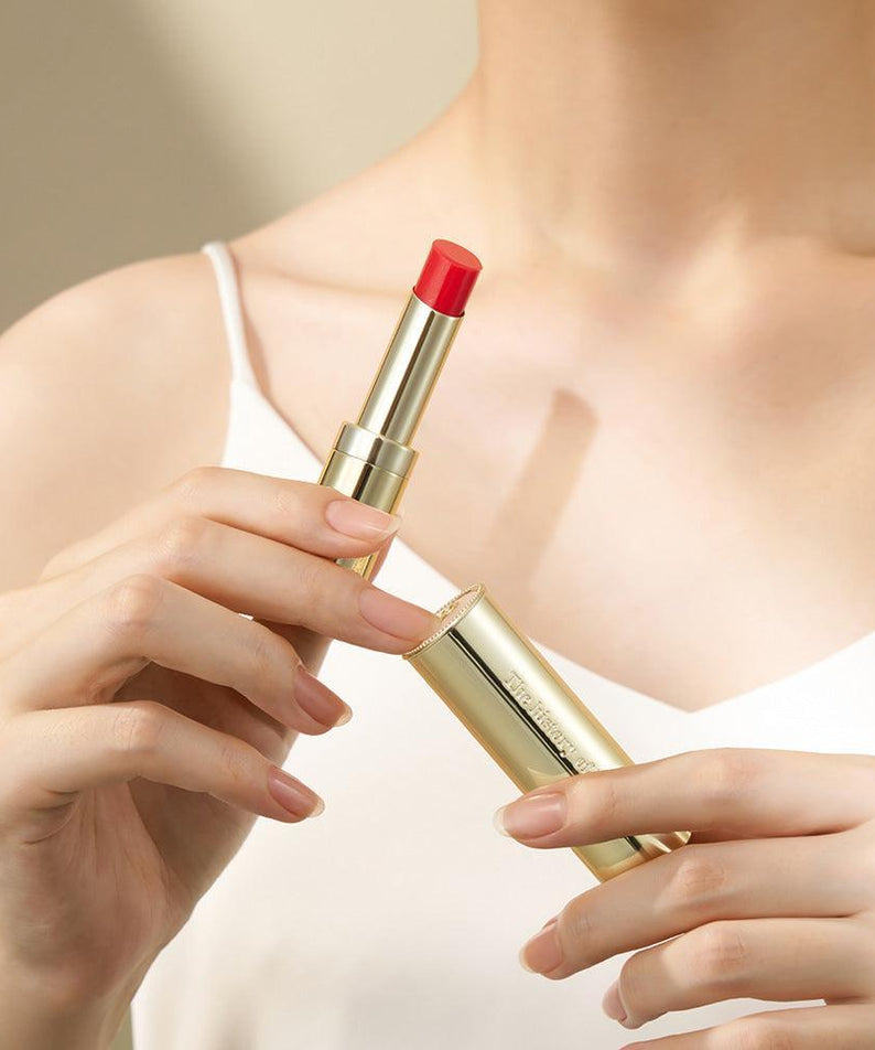 THE WHOO Gong Jin Hyang Mi Glow Lip Balm 3.3g tenu en main, beauté élégante avec emballage doré brillant.