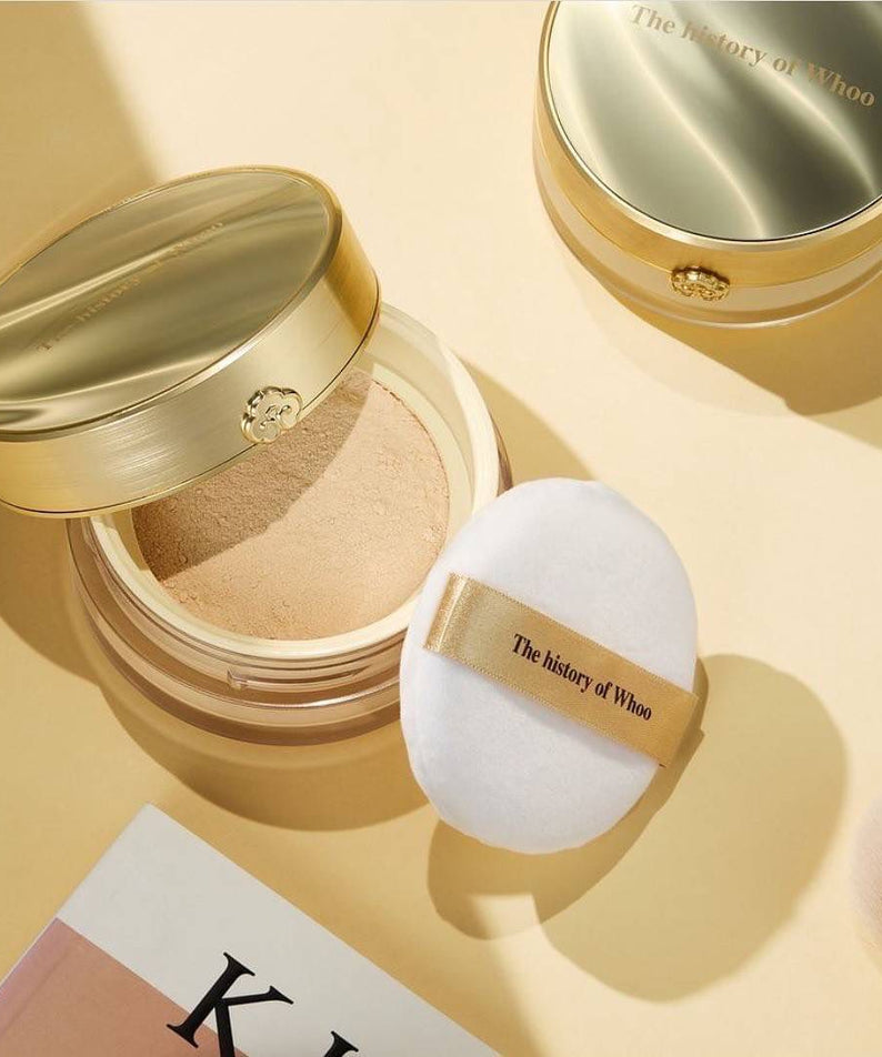THE WHOO Gong Jin Hyang Mi Luxury Luminous Powder en boîte dorée avec applicateur blanc, maquillage de luxe élégant.