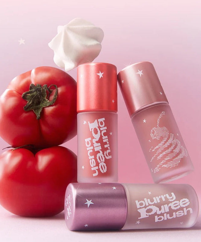 Produits TIP TOE Blurry Puree Blusher avec design unique, blusher flou et texture crémeuse, posés sur fond rose avec tomate.