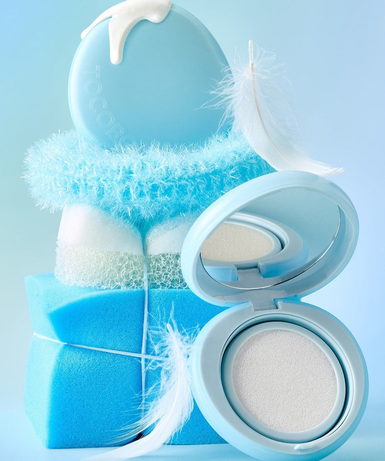 TOCOBO Blur Finish Sun Cushion, boîtier maquillage bleu sur fond ciel, texture poudre floue, style beauté.
