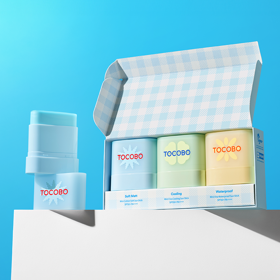 TOCOBO Mini Sun Stick Trio, produits TOCOBO sur fond bleu, pack et sticks à côté pour le maquillage et la protection solaire