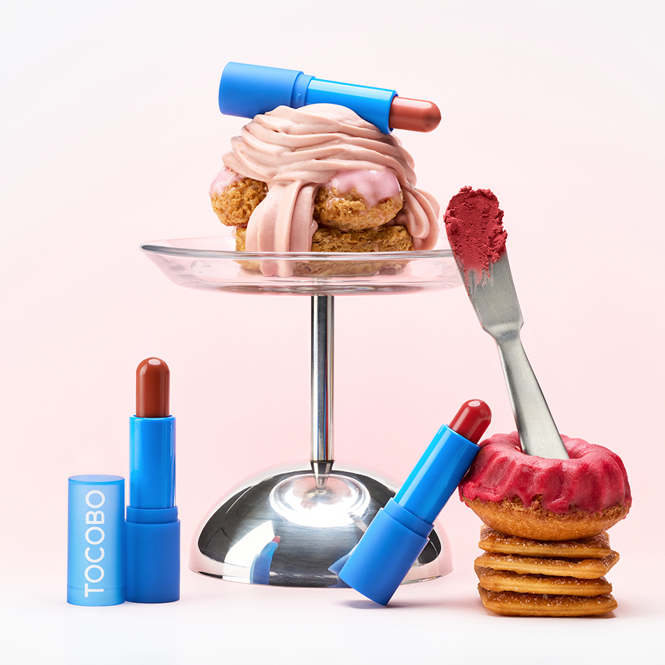 TOCOBO Powder Cream Lip Balm, tube bleu et baume rose sur fond rose, ambiance cosmétique gourmande