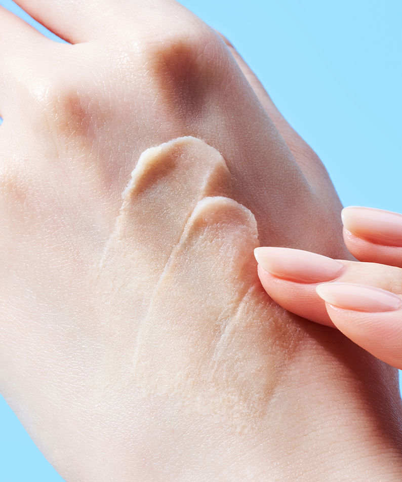 Texture légère du TOCOBO Vita Airy Sun Primer 35ml appliquée sur la main, montrant sa consistance crémeuse sur fond bleu.