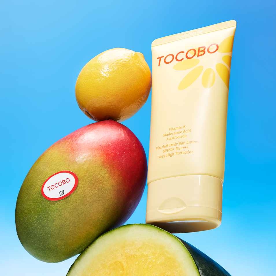 TOCOBO Vita Soft Daily Sun Lotion SPF50+ PA++++ 150ml, tube soleil sur fond bleu avec mangues et fruits.