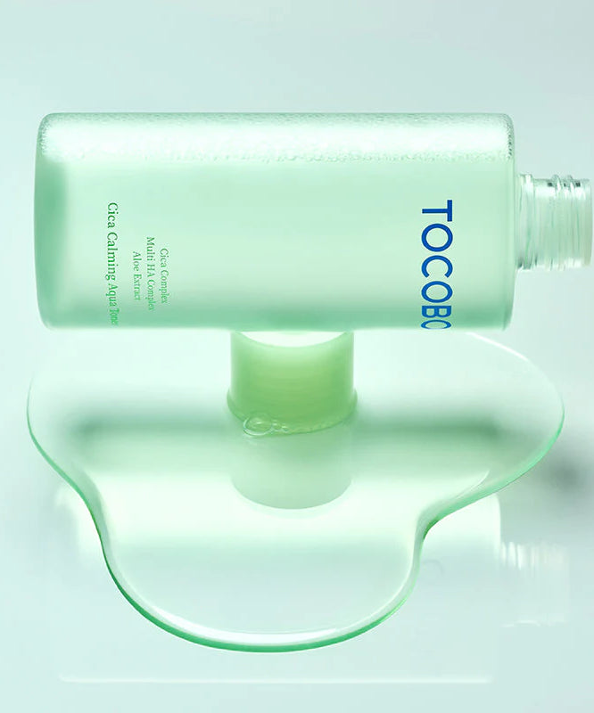 TOCOBO Cica Calming Aqua Toner, flacon vert sur fond turquoise, marque TOCOBO, ambiance soins visage apaisants.