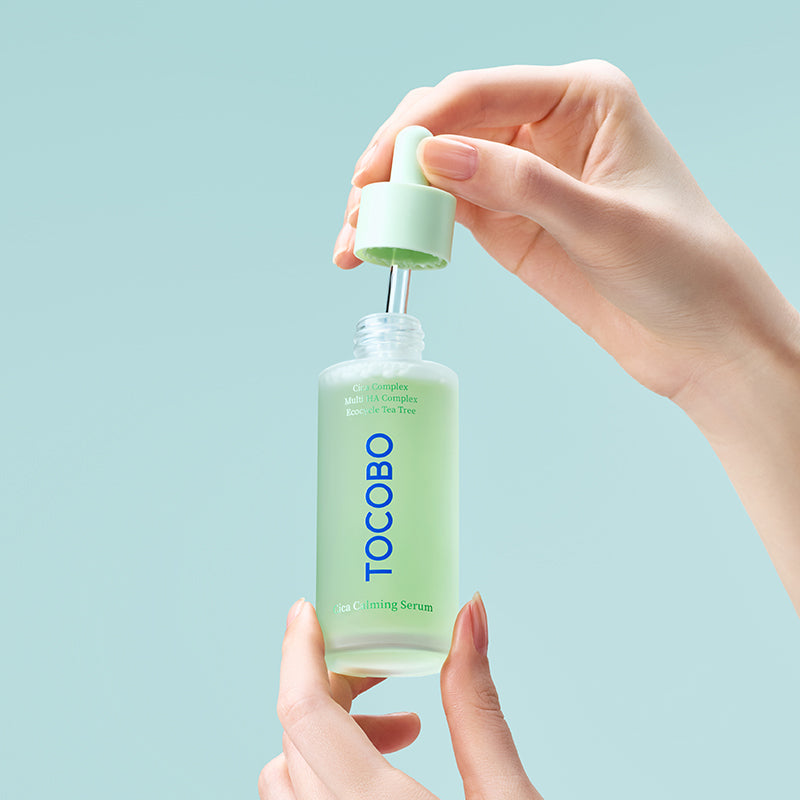 Main tenant TOCOBO Cica Calming Serum, flacon crème Cica, marque TOCOBO sur fond bleu clair, soin apaisant