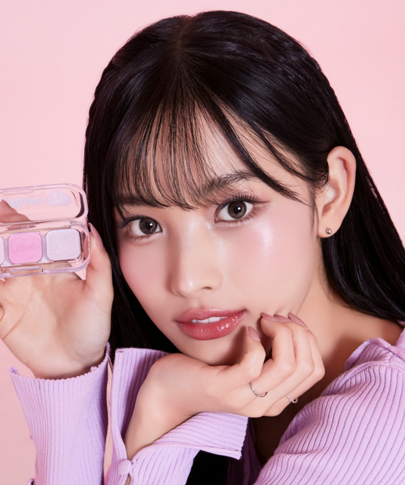 TONY MOLY Eyetone Eyeshadow Palette, femme maquillée tenant la palette, teintes pastel sur fond rose. Marque TONY MOLY.