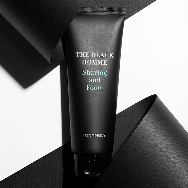 TONYMOLY The Black Homme Shaving & Foam 150g : tube noir sur fond tissu sombre, visuel produit en studio.