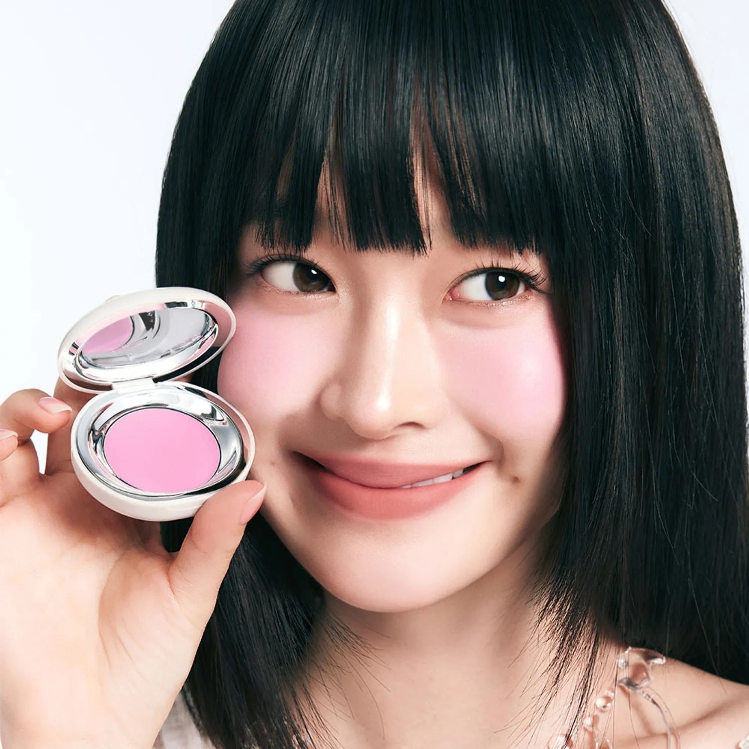 TOOQ Satin Peach Blossom : la marque TOOQ, maquillage en poudre rose pêche sur fond clair, visage souriant tenant le produit