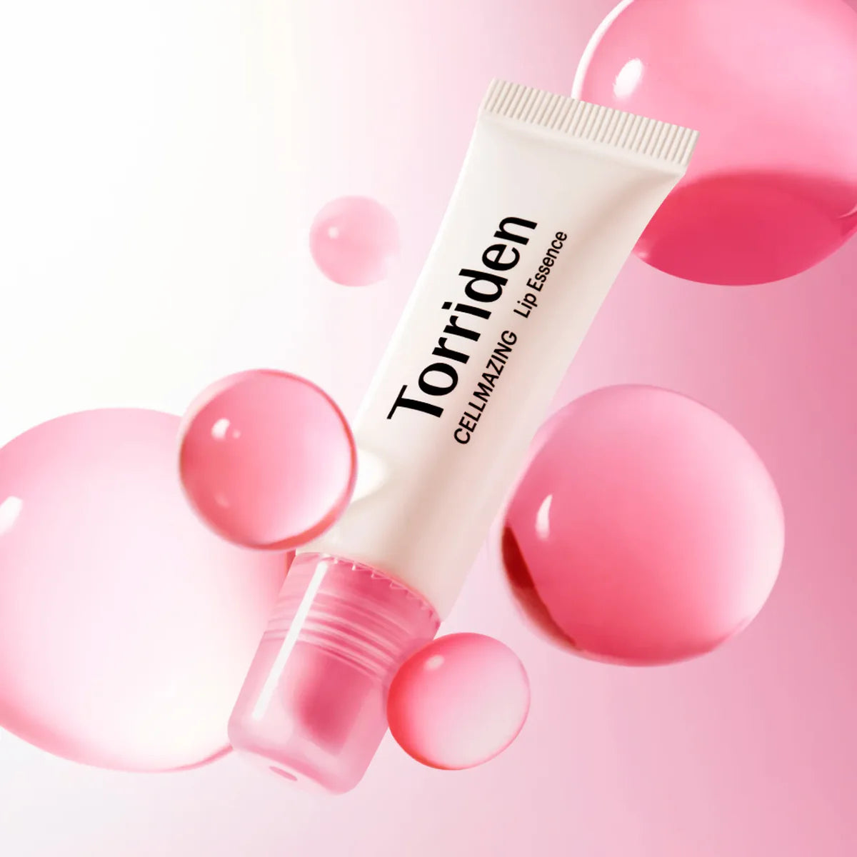 Décris l'image en français: TORRIDEN Cellmazing Low Molecular Collagen Volume Lip Essence 11ml, tube Torriden sur fond rose, bulles.