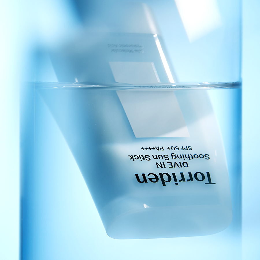 TORRIDEN Dive In Soothing Sun Stick SPF50+PA++++ 19g, stick solaire apaisant sur fond bleu lumineux, marque TORRIDEN
