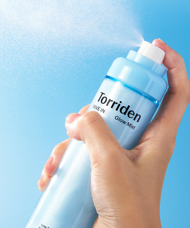 TORRIDEN Dive-in Low Molecular Hyaluronic Acid Cream Mist 120ml, main tenant le flacon sur fond bleu aquatique.