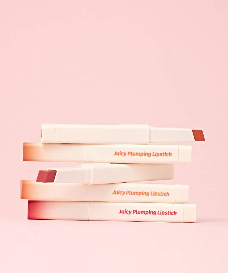 TOUCH IN SOL Vegan Again Juicy Plumping Lipstick de TOUCH IN SOL, présentés sur fond rose pastel, tubes alignés.