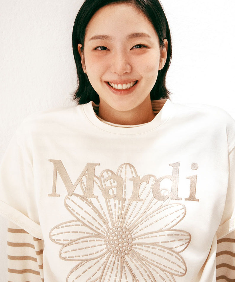 TSHIRT FLOWERMARDI NEEDLEWORK_CREAM BEIGE Mardi Mercredi : mannequin souriant, t-shirt crème avec broderie fleur, fond clair.