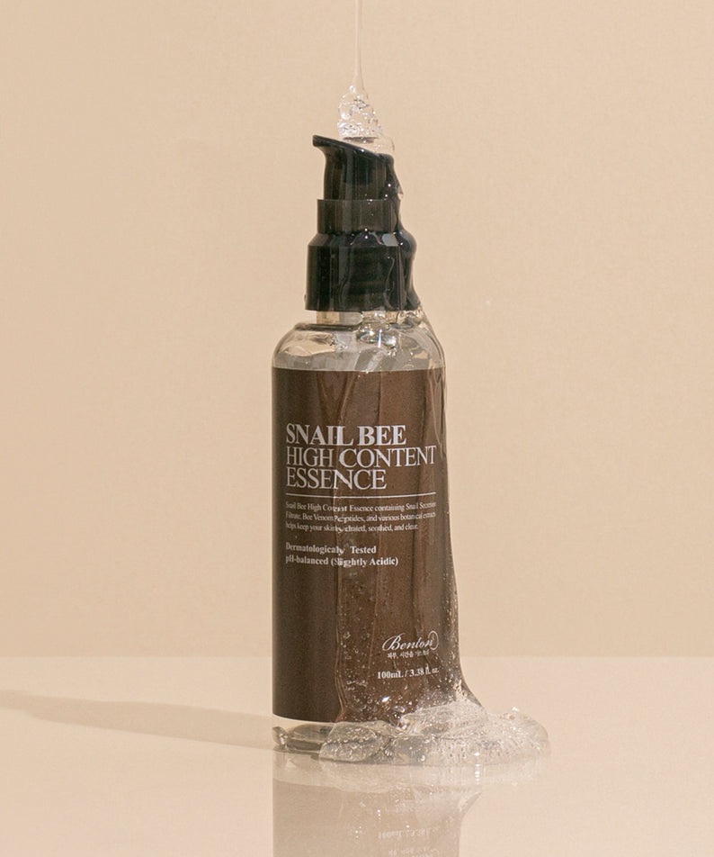BENTON Snail Bee High Content Essence 100ml, flacon cosmétique Benton sur fond beige, vue studio.