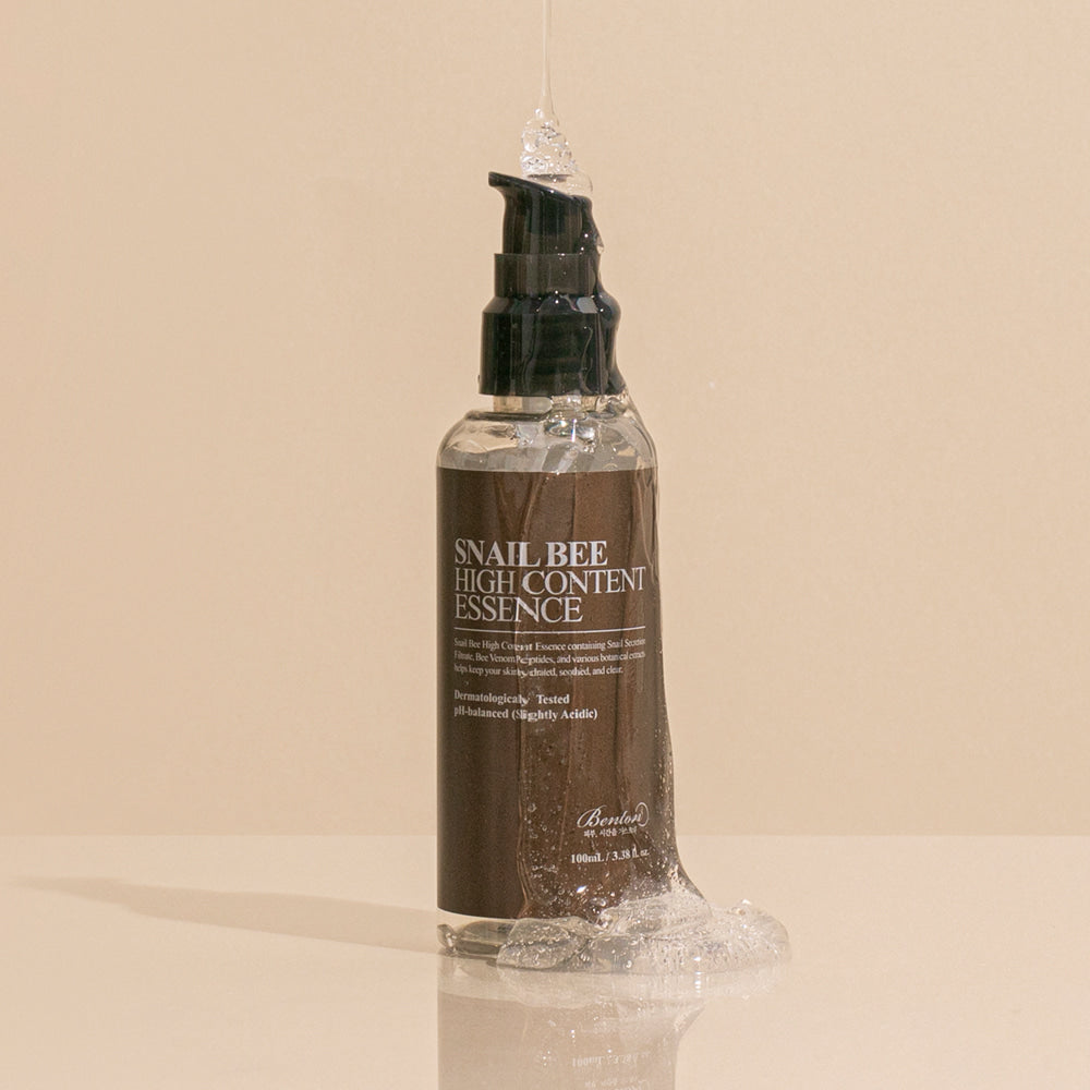 BENTON Snail Bee High Content Essence 100ml, flacon cosmétique Benton sur fond beige, vue studio.