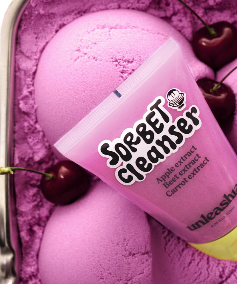UNLEASHIA ABC Sorbat Facial Cleanser 120ml, flacon rose sur fond violet avec éléments de pomme et cœurs, marque UNLEASHIA