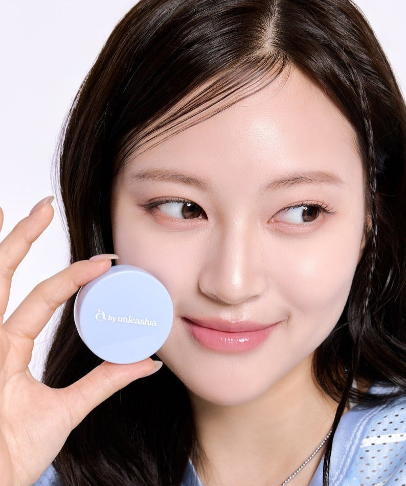 UNLEASHIA Be Be Blue Cushion : femme tient le compact bleu en studio, maquillage visage, fond clair.
