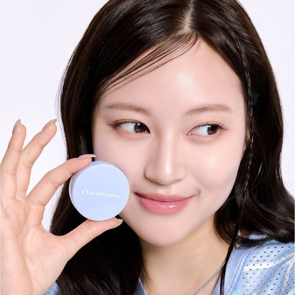 UNLEASHIA Be Be Blue Cushion : femme tient le compact bleu en studio, maquillage visage, fond clair.