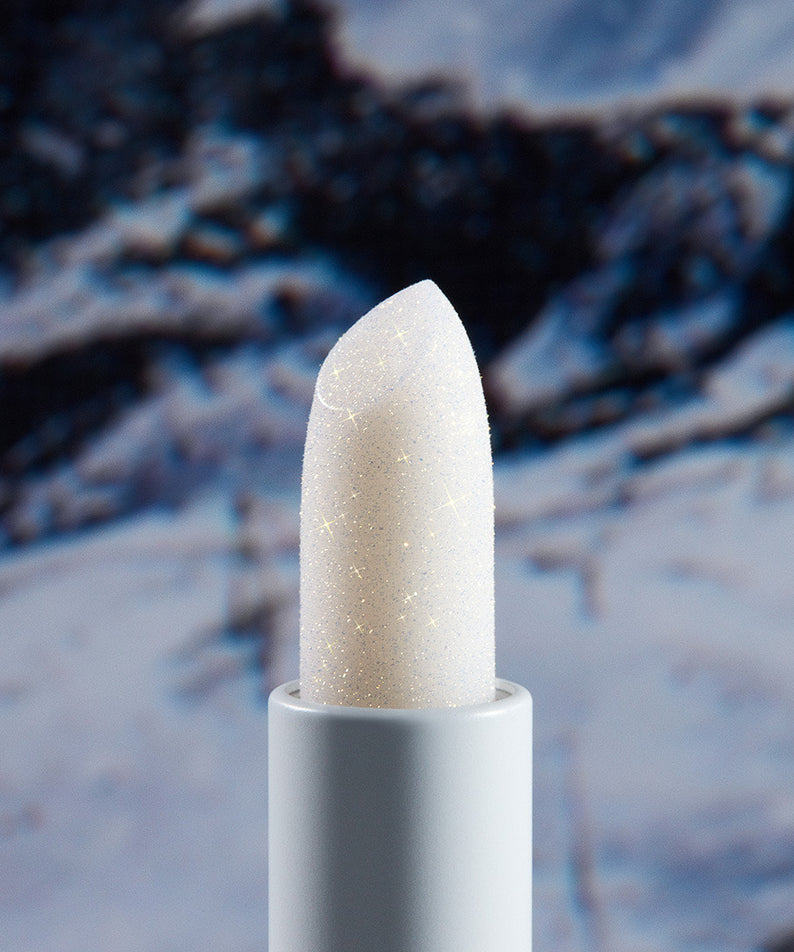 Baume à lèvres UNLEASHIA Glacier Vegan, texture crémeuse et brillante, avec fond de paysage glaciaire imposant.