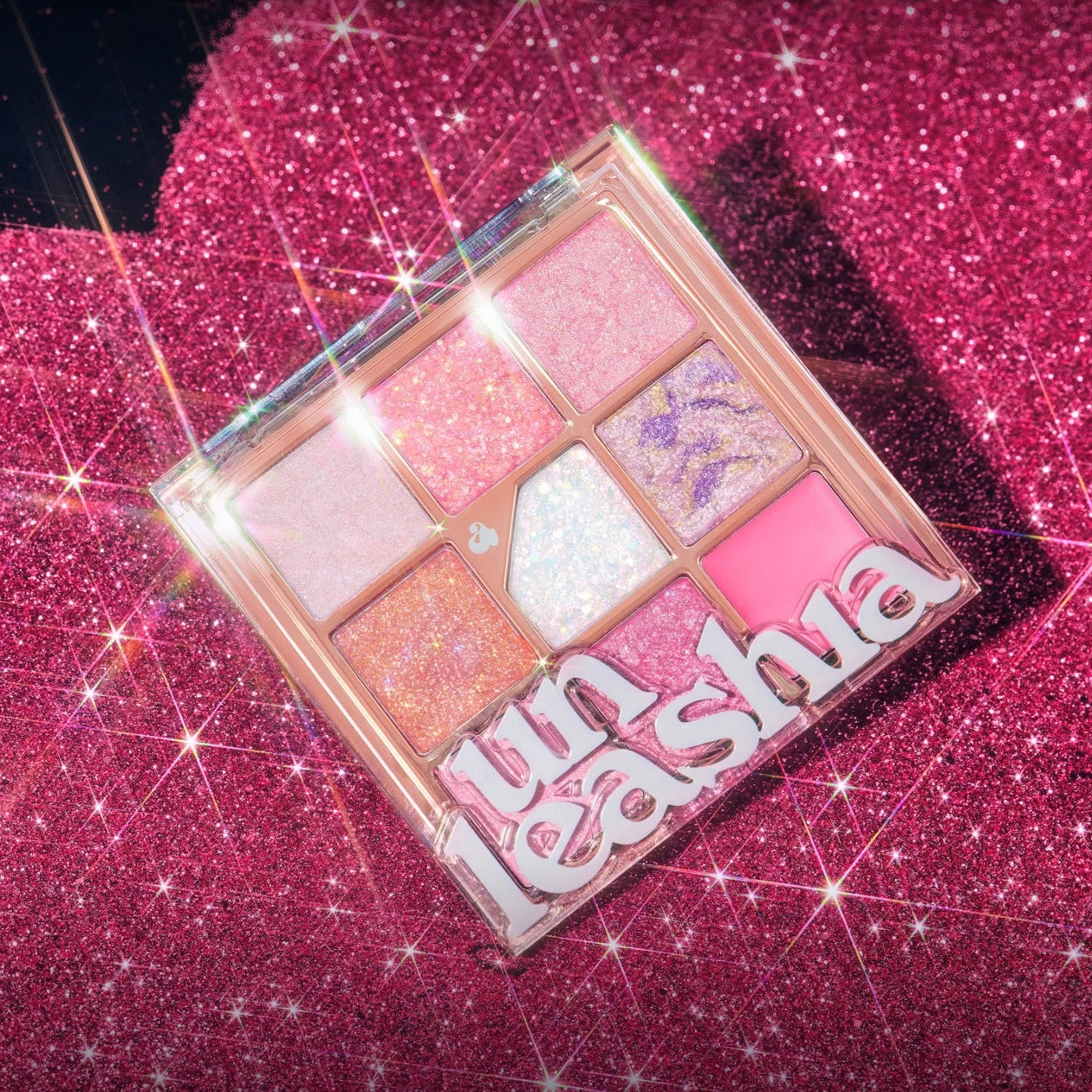 UNLEASHIA Glitterpedia Eye Palette de UNLEASHIA sur fond pailleté rose, palette d’ombres aux teintes irisées.