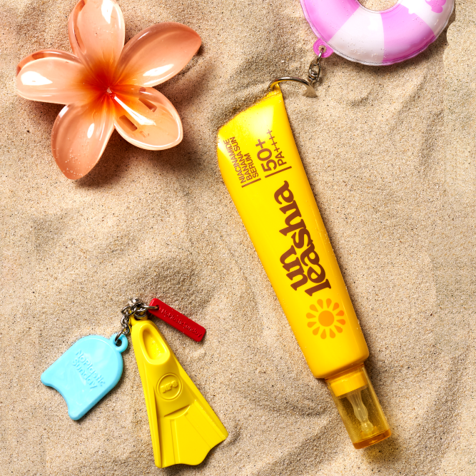 UNLEASHIA Niacinamide Banana Sun Serum 40ml de la marque UNLEASHIA, posé sur sable avec fleurs et accessoires au soleil.