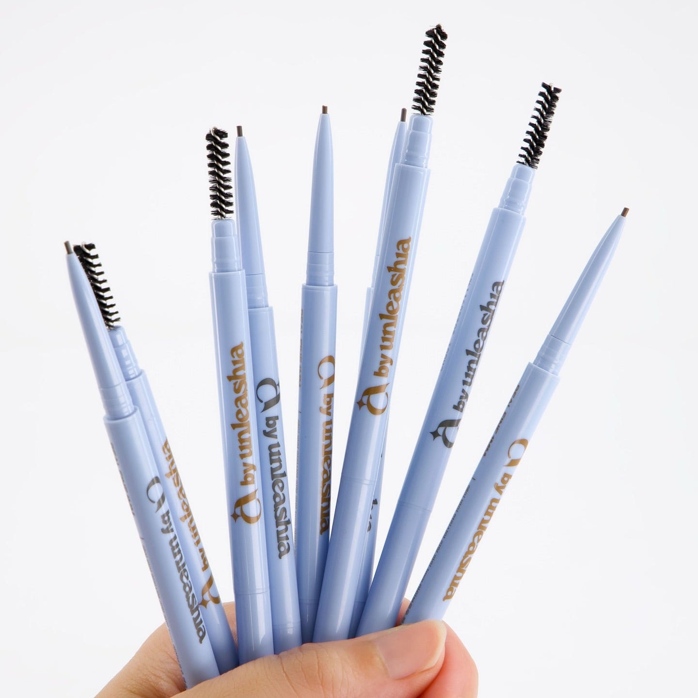 UNLEASHIA Real Fine 1mm Eyebrow Pencil, crayons sourcils UNLEASHIA, gros plan sur des stylos bleus, toile blanche.