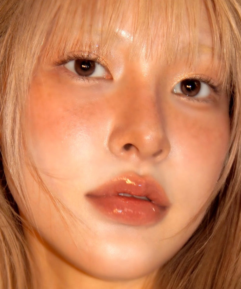 Femme portant UNLEASHIA Sunset Dazzle Gloss Balm avec brillance lumineuse sur lèvres, maquillage subtil et élégance naturelle.