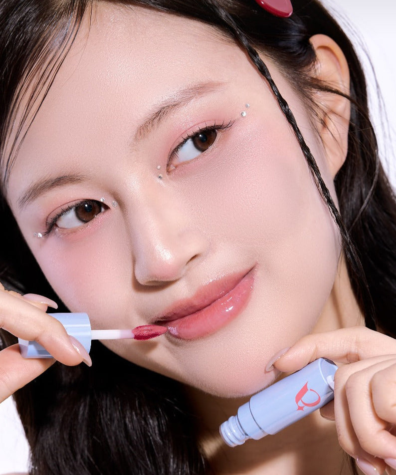 UNLEASHIA Tanghulu Glaze Tint, femme applique un gloss rose sur fond clair, marque UNLEASHIA en contexte beauté.
