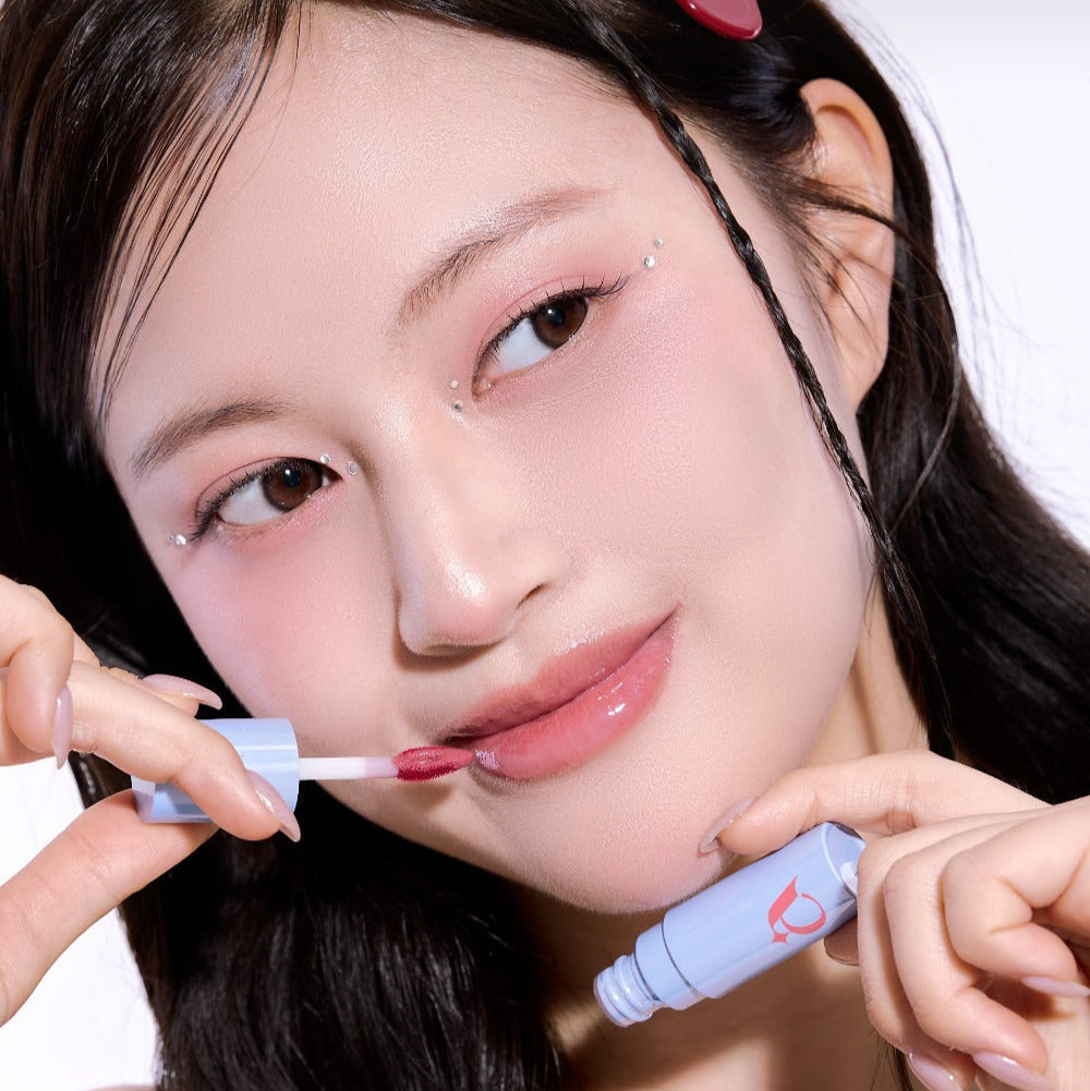 UNLEASHIA Tanghulu Glaze Tint, femme applique un gloss rose sur fond clair, marque UNLEASHIA en contexte beauté.