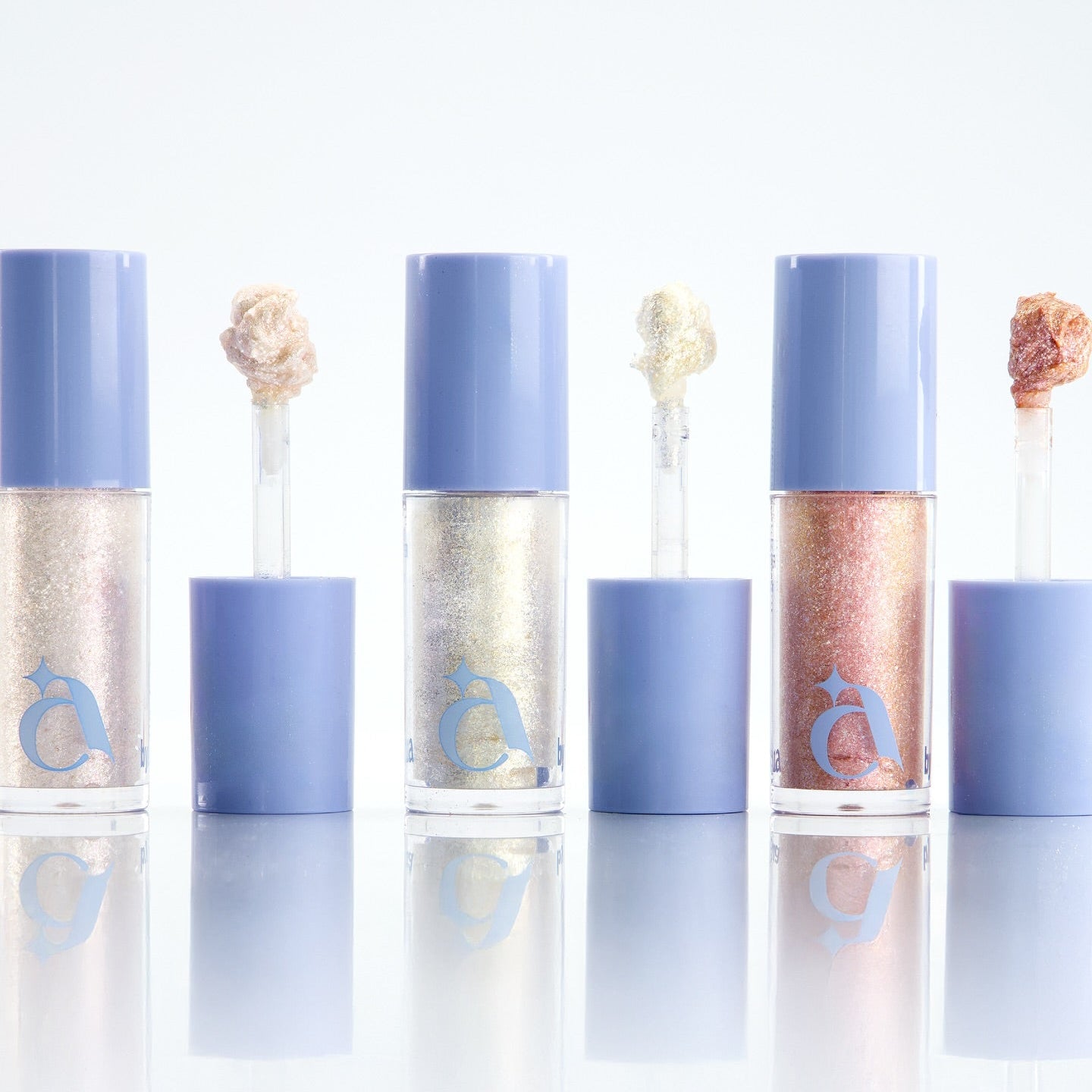UNLEASHIA the Moonlight Liquid Glitter : flacons liquides pailletés bleu, or et rose sur fond blanc, décor lune.