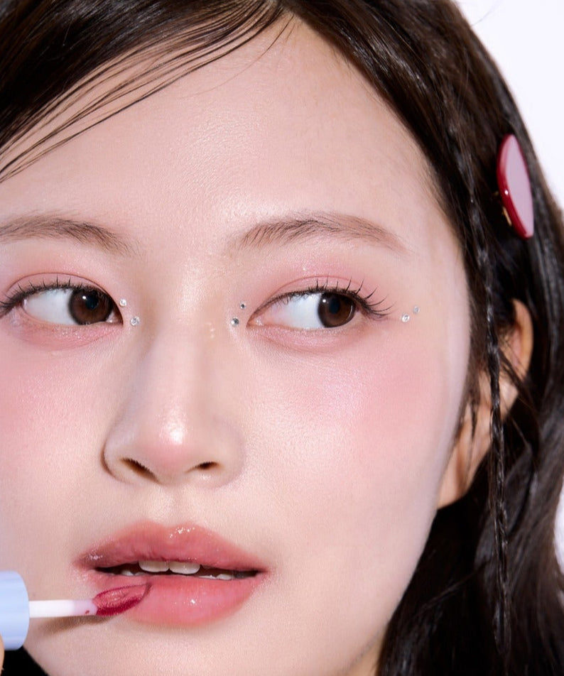 Femme appliquant UNLEASHIA Tanghulu Glaze Tint, créant un look glamour et brillant.