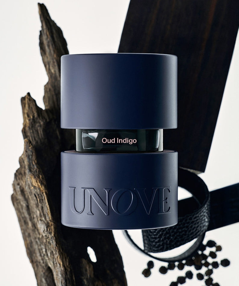 UNOVE Eau De Parfume de la marque UNOVE, flacon bleu sur étagère, contexte luxe avec décor noir et perles.