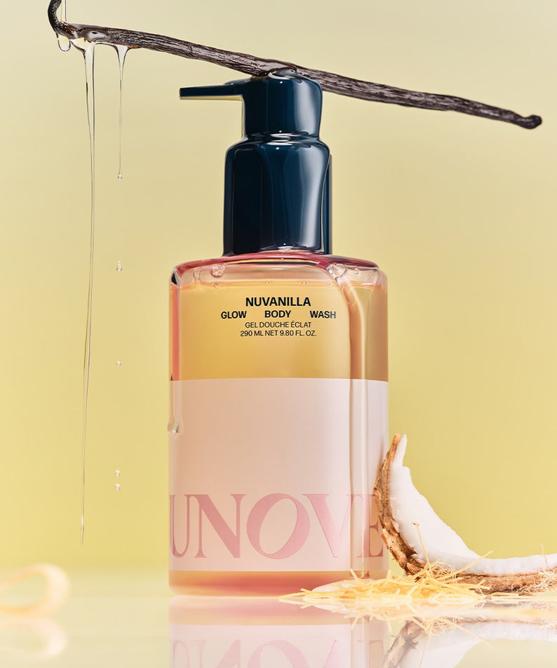 UNOVE Glow Body Wash 290ml de marque UNOVE, flacon rose sous un jet d’eau, fond jaune lumineux, produit en gros plan