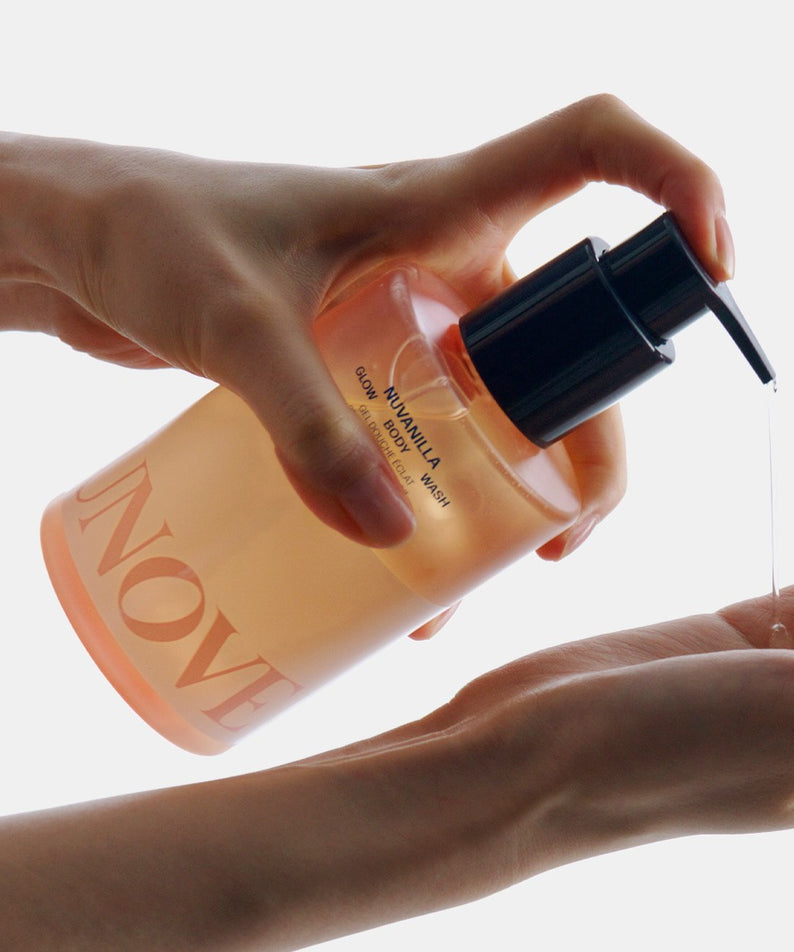 UNOVE Glow Body Wash 290ml, flacon en main, mains tenant le produit sur fond clair, contexte visuel maquillage
