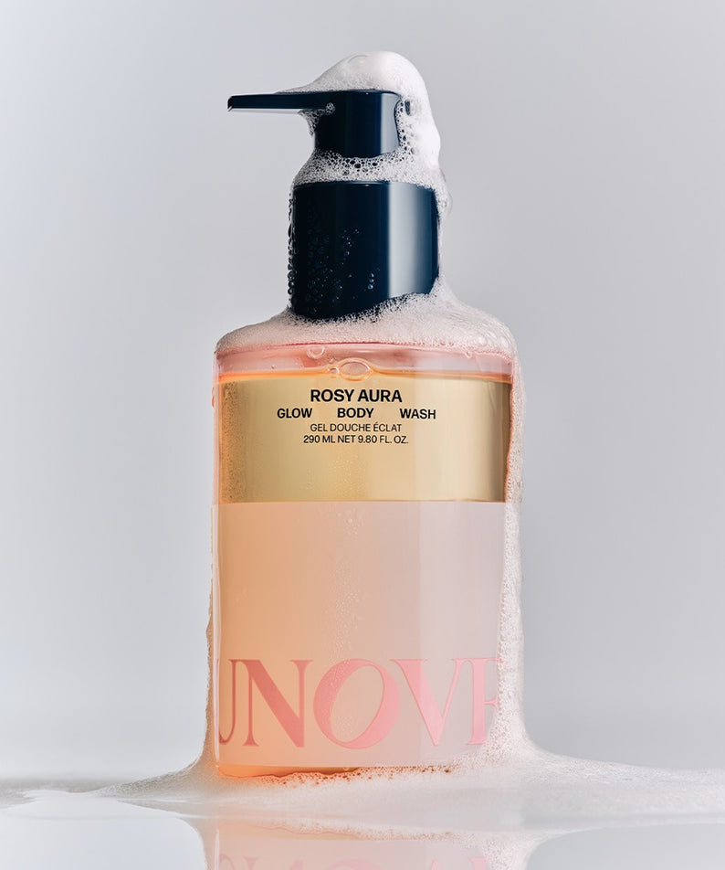 UNOVE Glow Body Wash 290ml, bouteille UNOVE sur fond blanc avec mousse et éclaboussures, contexte douche